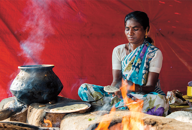Enlargeable photo of Indian woman cooking flatbread over open flame
