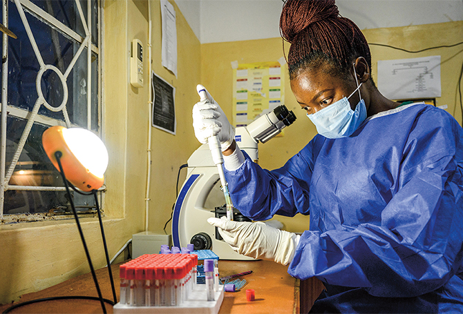 Enlargeable photo of lab technician working by light of solar lamp