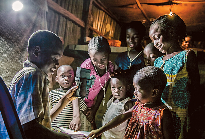 Enlargeable photo of children reading at night under the light of a solar lamp