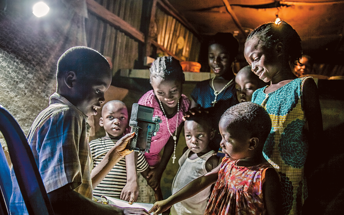 Children reading at night under the light of a solar lamp