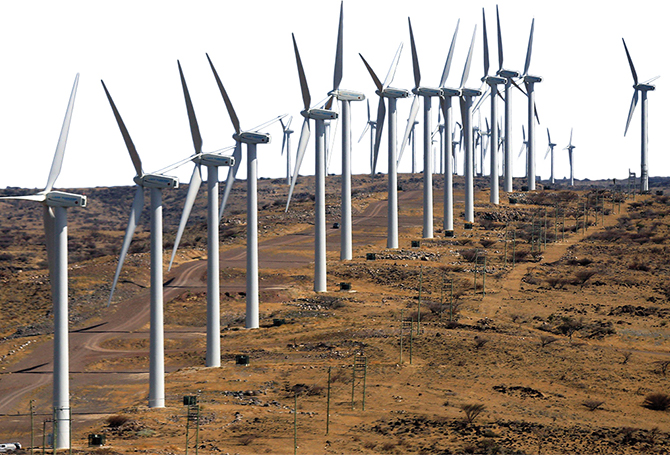 Enlargeable photo of wind turbines lining a road in an arid environment