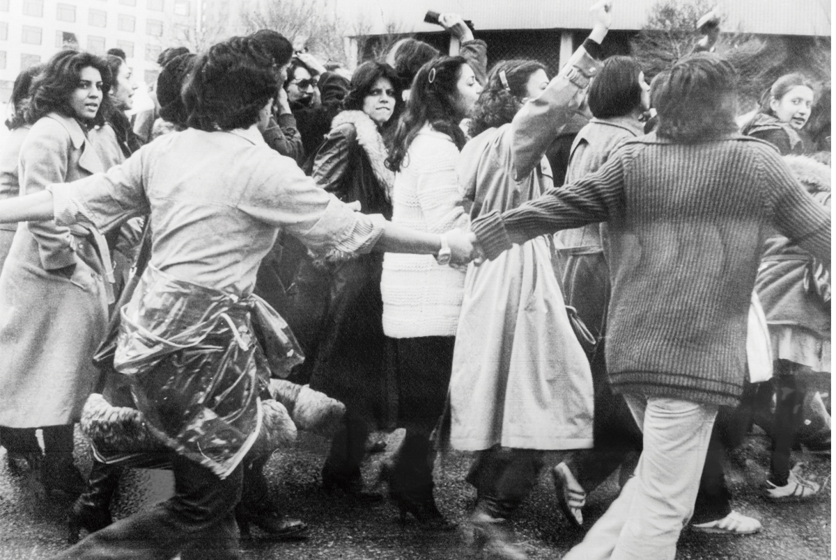 Black & white photo of a crowd of people protesting and some running & holding hands