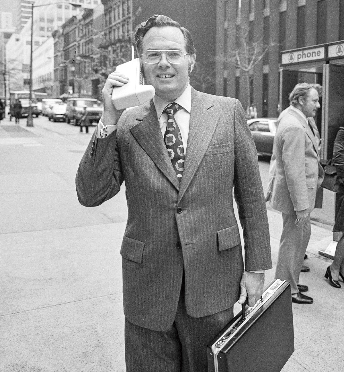 Black & white photo of a businessman using a large cell phone
