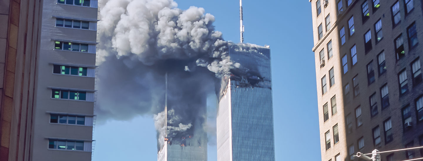 Historical photo of the Twin Towers with smoke and flames rising from both buildings on September 11, 2001