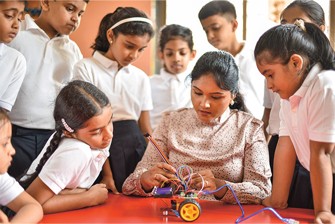 Enlargeable photo of a teacher demonstrating an experiment while students are gathered around her